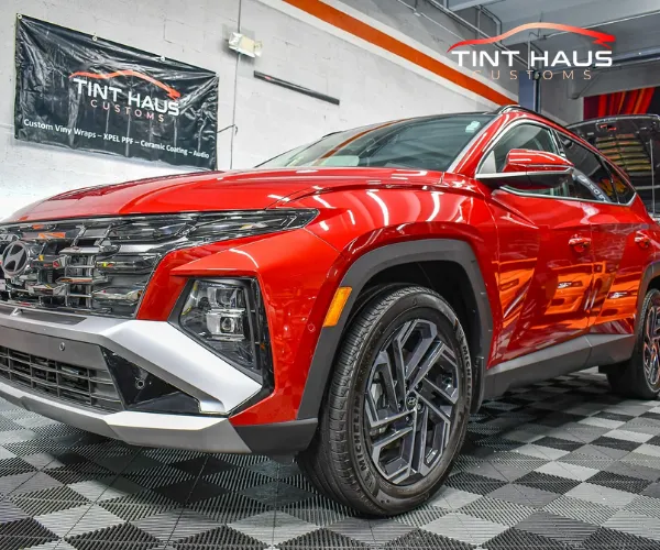 A bright red SUV with a glossy finish parked in a professional auto shop featuring a checkered floor and shop branding.